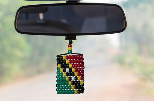 Colorful beaded car hanging ornament on a car's rearview mirror with a blurred road background.